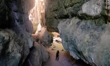 A traveler explores the stunning rock formations and narrow canyon passage near Cunca Wulang Waterfalls, showcasing the natural beauty and adventure of Labuan Bajo’s hidden gem in Flores, Indonesia.
