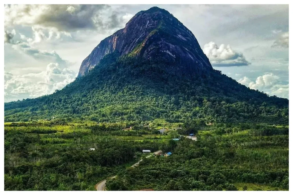 Lush tropical landscape with a towering mountain rising above dense rainforest, highlighting one of the best treks in Indonesia with scenic jungle trails and panoramic summit views.
